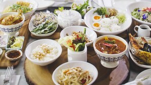 A dining table with various dishes and a sofa with patterned cushions. - The Raweekanlaya Hotel Bangkok (Bangkok)
