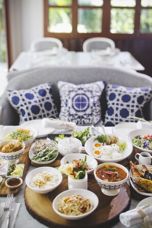 Une table à manger avec différents plats et un canapé agrémenté de coussins à motifs.