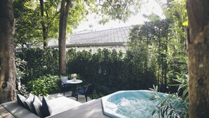A hot tub surrounded by lush greenery, a wooden deck, and a dining area with chairs and a table. - The Raweekanlaya Hotel Bangkok (Bangkok)