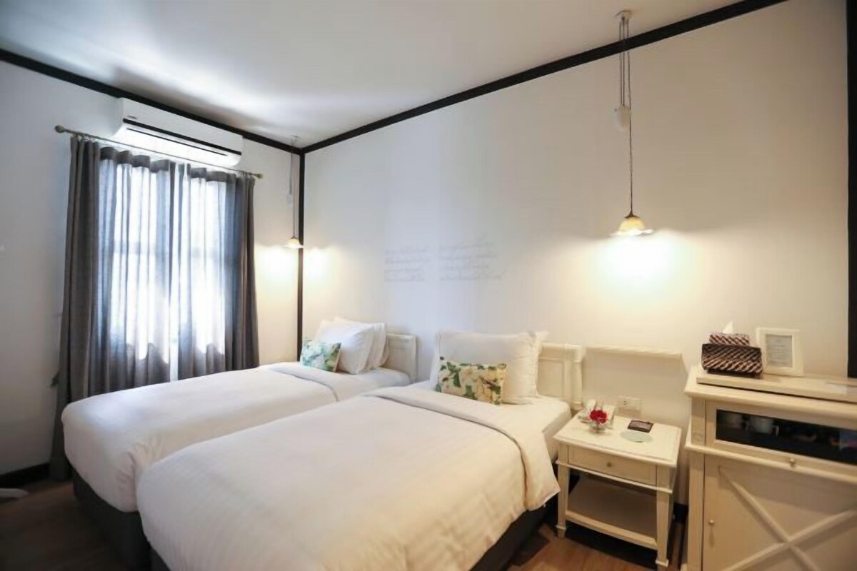 Une chambre d’hôtel avec deux lits, une petite table de chevet avec une lampe et une armoire.