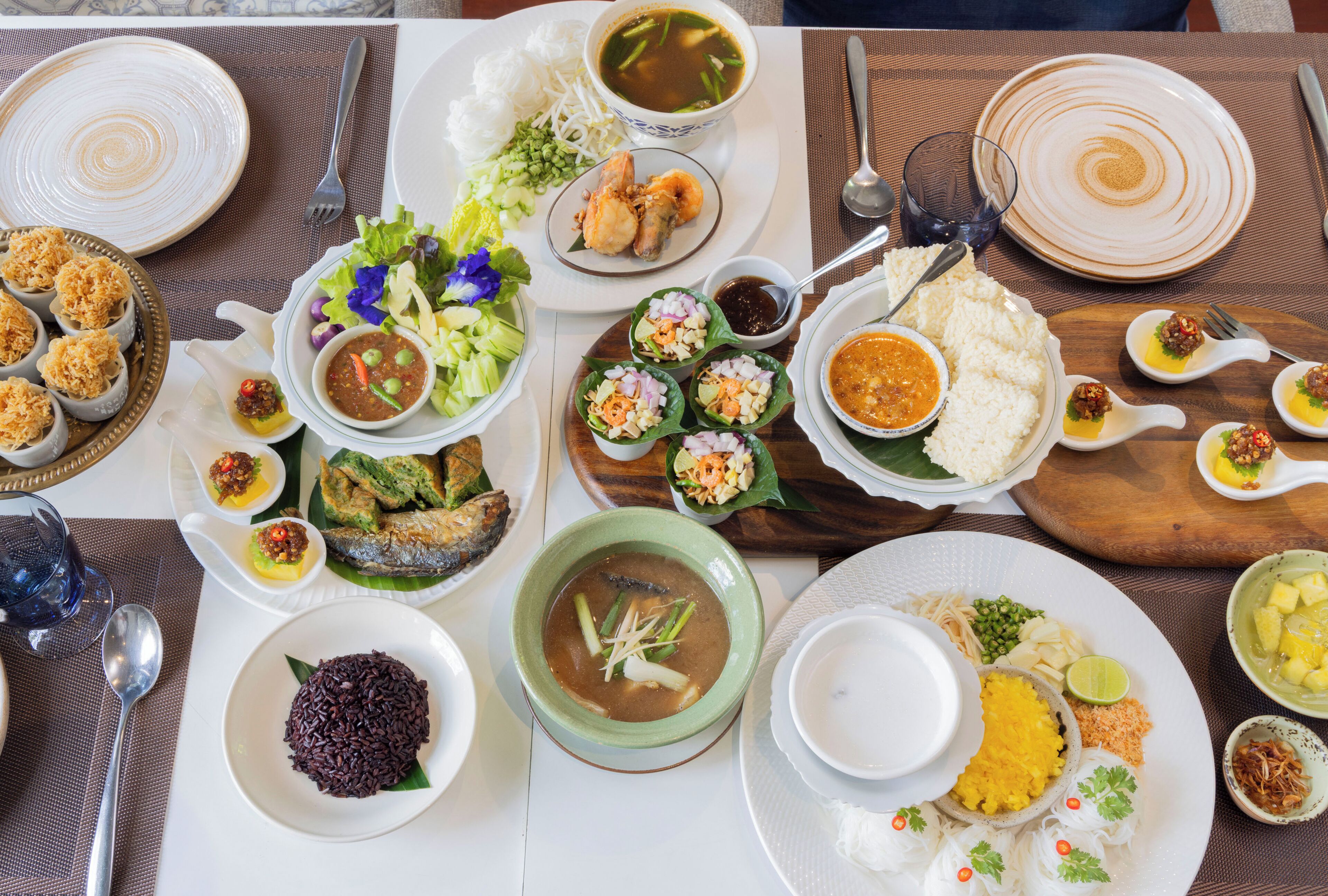 Une table garnie de différents plats, notamment du riz, de la soupe et de la viande.