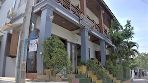 A building with a balcony, multiple potted plants, and a signboard. - Visoun Namsok Hotel (Luang Prabang)
