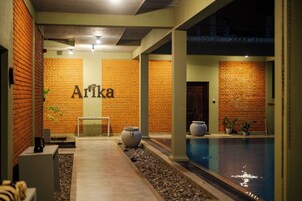 Vestíbulo de hotel con pared de ladrillo, piscina y mostrador de recepción.