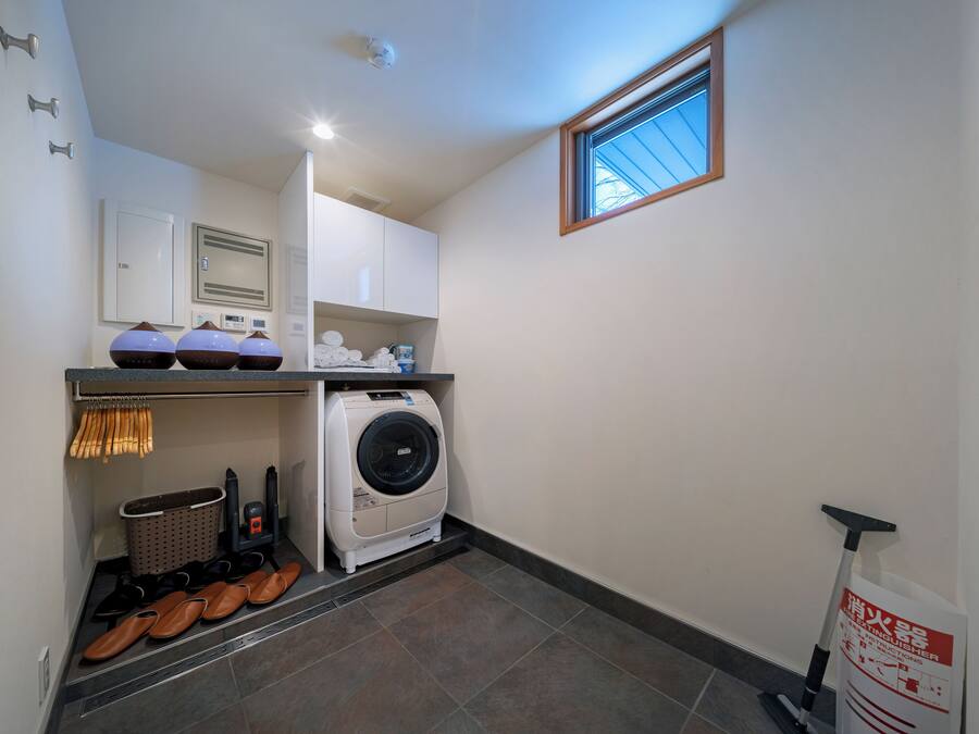 A laundry room with a washing machine, drying rack, and shoe rack.