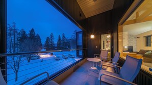 Een modern interieur met een balkon met uitzicht op een besneeuwde straat in de schemering.