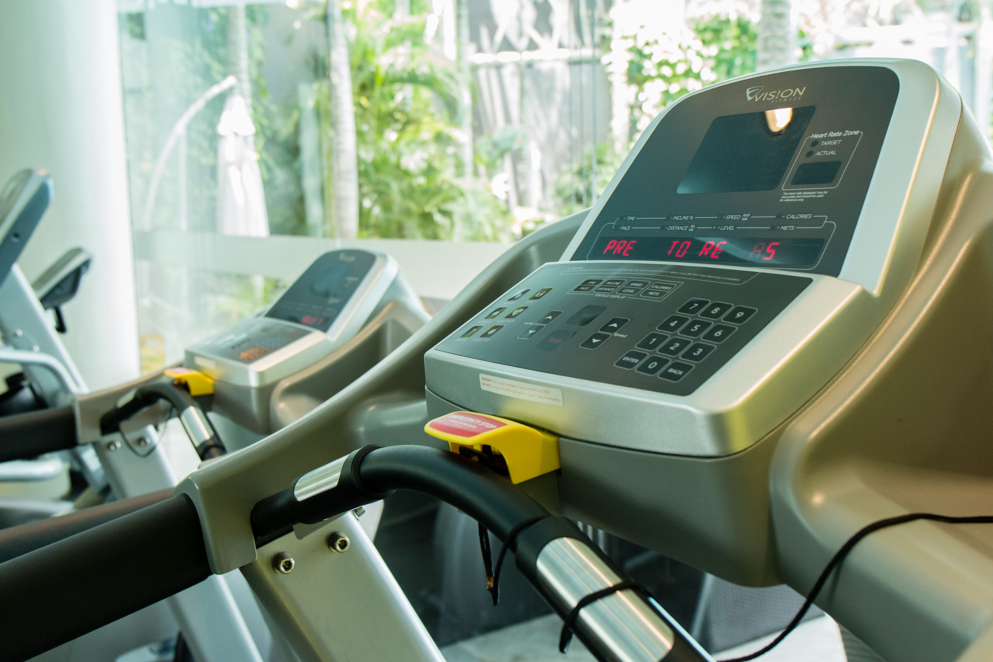 Ein stationäres Fahrrad mit digitalem Display und einem gelben Knopf, vermutlich in einem Fitnessstudio oder Fitnesszentrum.