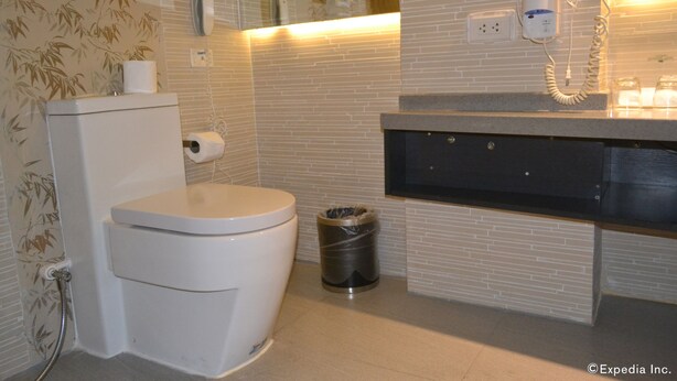 Un baño con inodoro, cubo de basura, secador de pelo y espejo.