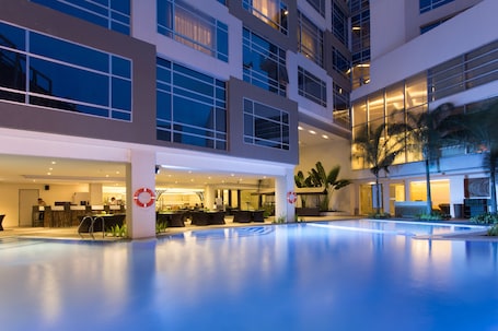 Una piscina al aire libre, sombrillas, sillones reclinables de piscina