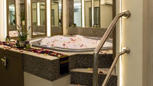 Zona de spa con hidromasaje, una escalera y un espejo que refleja la habitación.