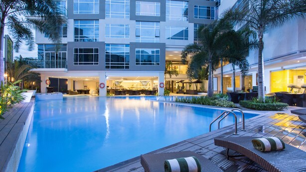 Un hotel moderno con piscina, zona de estar al aire libre y un vestíbulo bien iluminado.