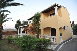 A two-story house with a balcony, surrounded by greenery and a stone wall. - Saint Spiridon Hotel (Corfu)