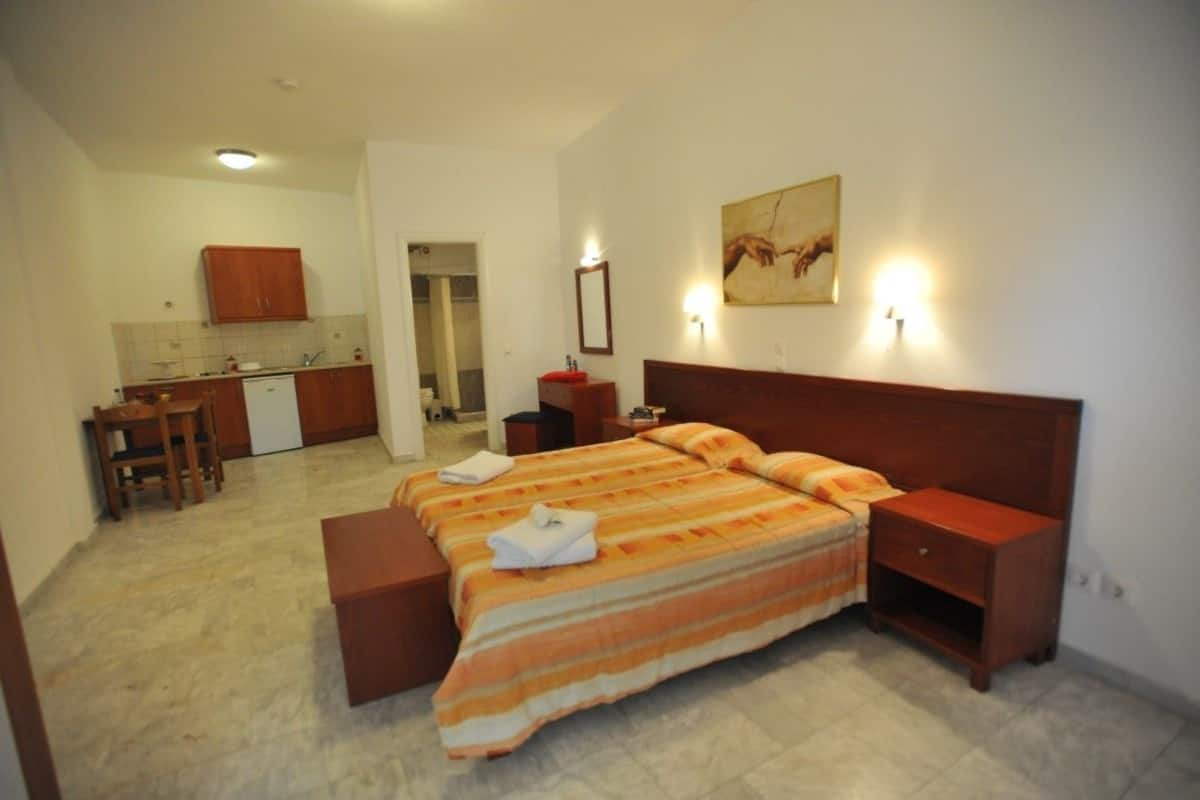 Ein Hotelzimmer mit Bett, Schreibtisch und Küchenzeile.