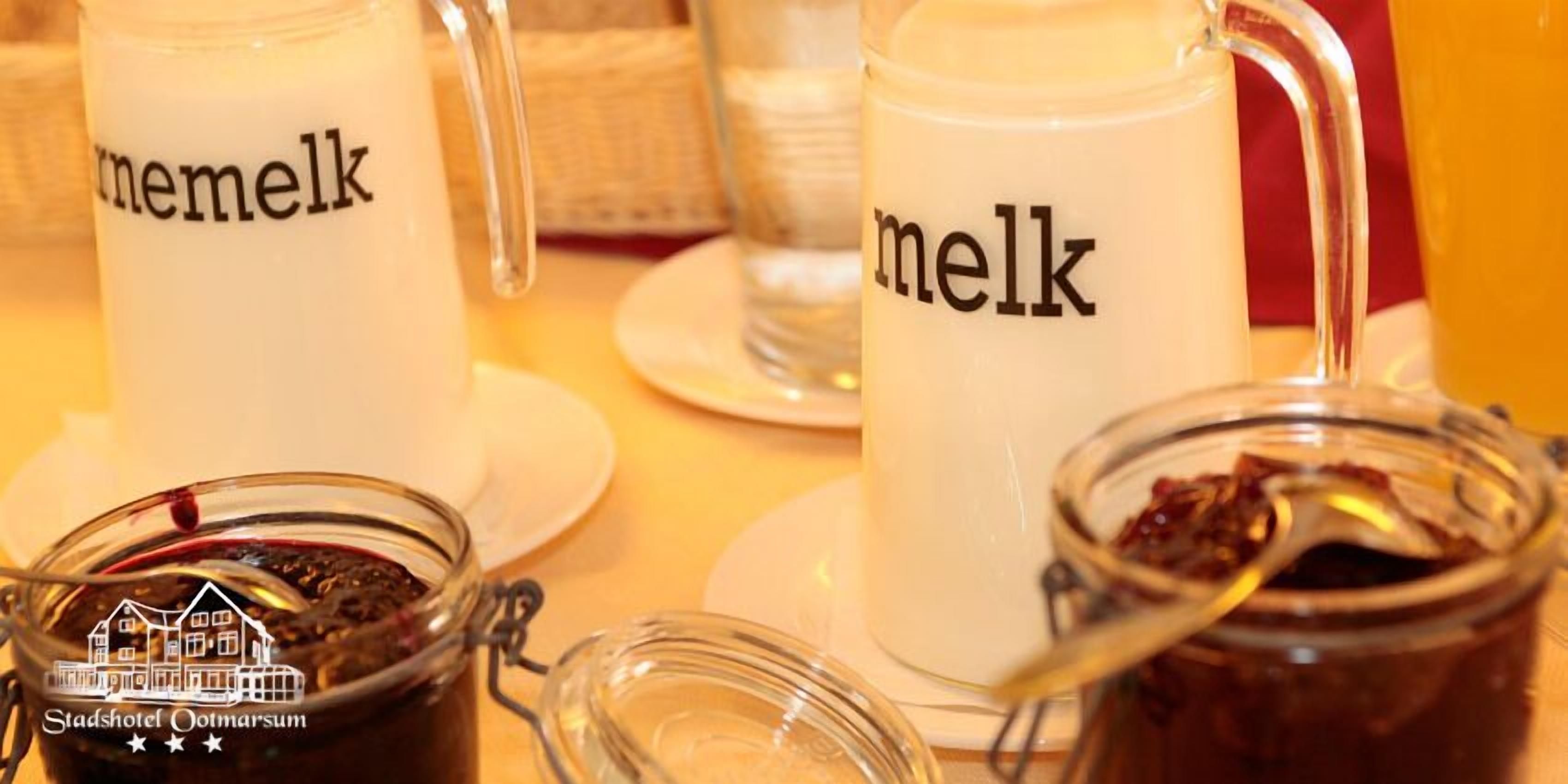 Três milkshakes com a palavra 'melk' escrita nelas, um pote de vidro com uma colher e o logotipo do Stadshotel Ootmarsum.