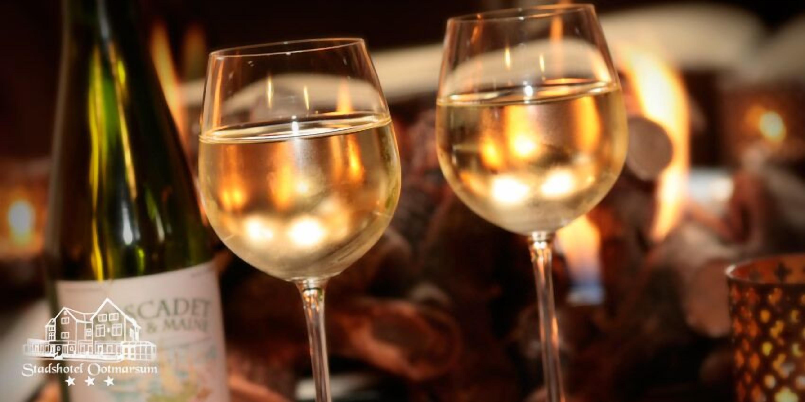 Deux verres de vin blanc, avec une bouteille en arrière-plan.