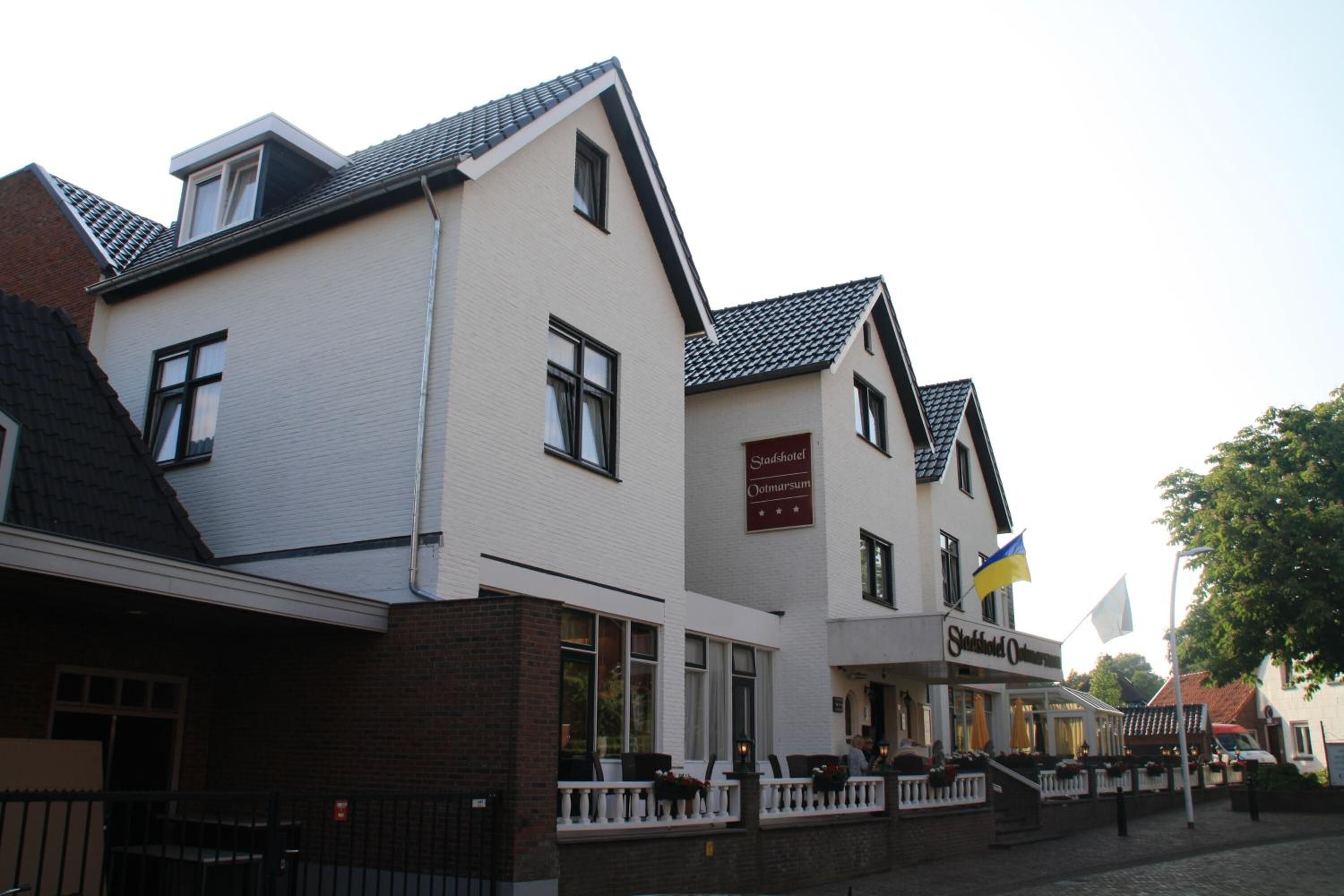 A row of white buildings with a sign for 'Stadshotel Oltmarsum' and a Ukrainian flag.