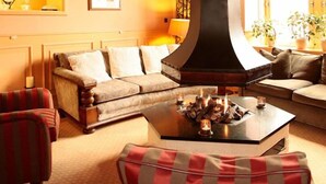 Un salon chaleureux avec une cheminée, un canapé et une table basse agrémentée de bougies.