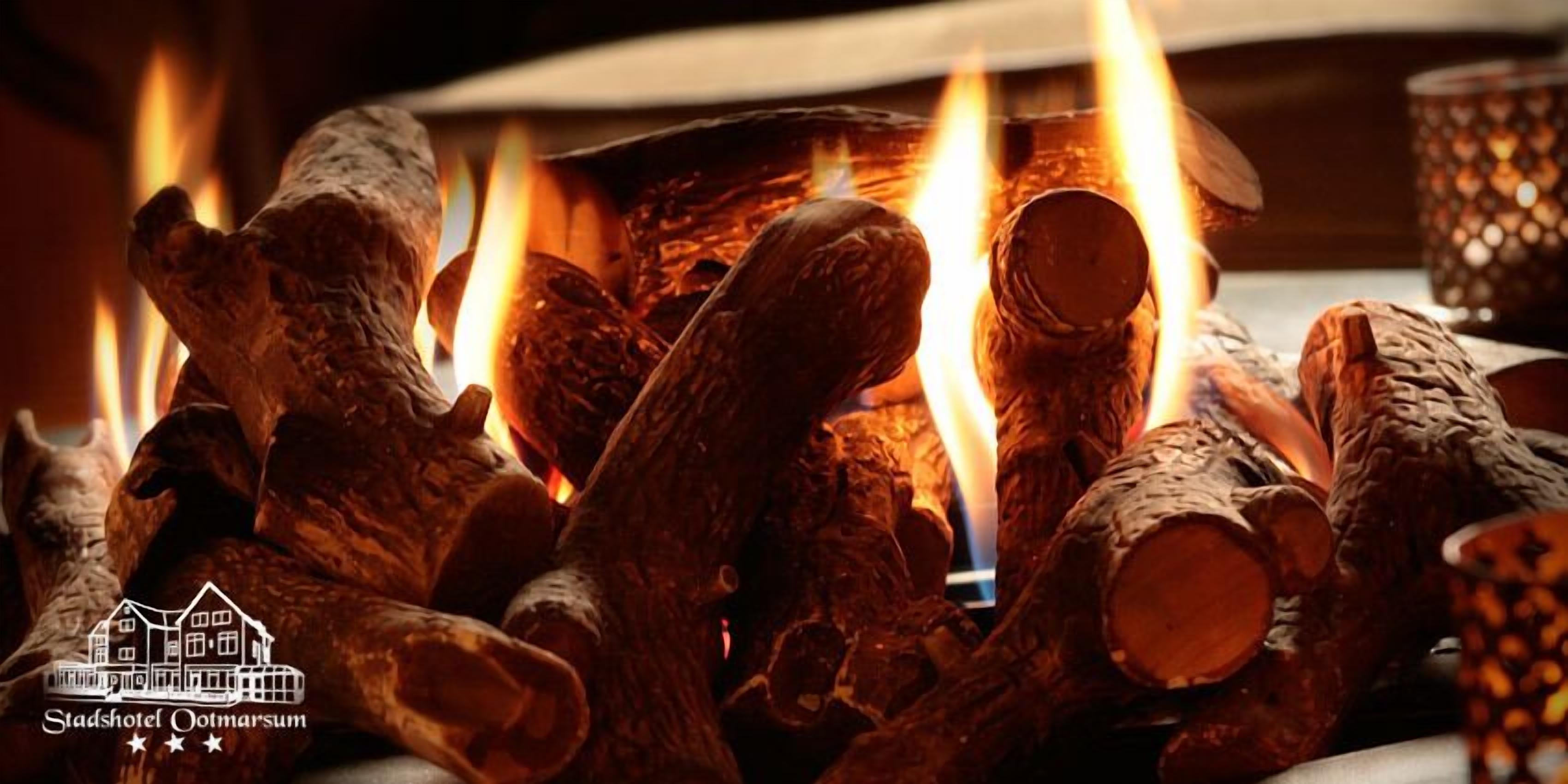 A fireplace with logs burning, a candle holder, and a logo for Stadshotel Ootmarsum.