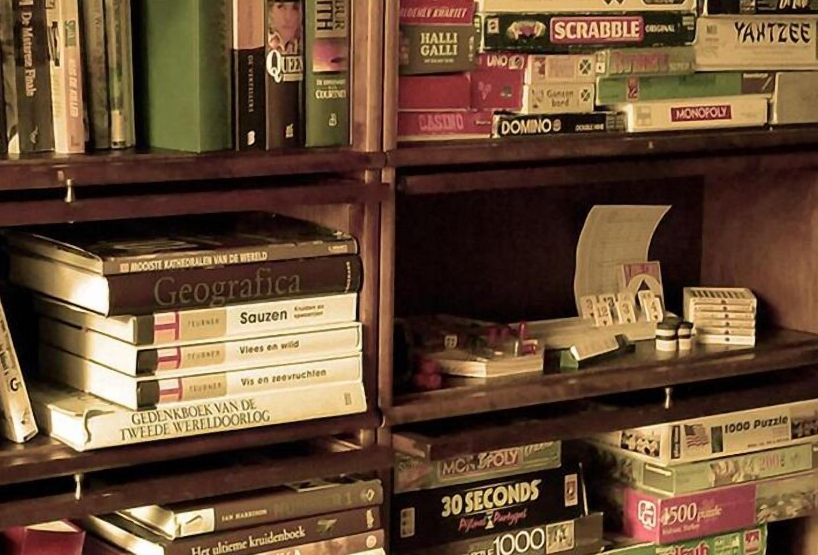 A bookshelf with various board games and books.