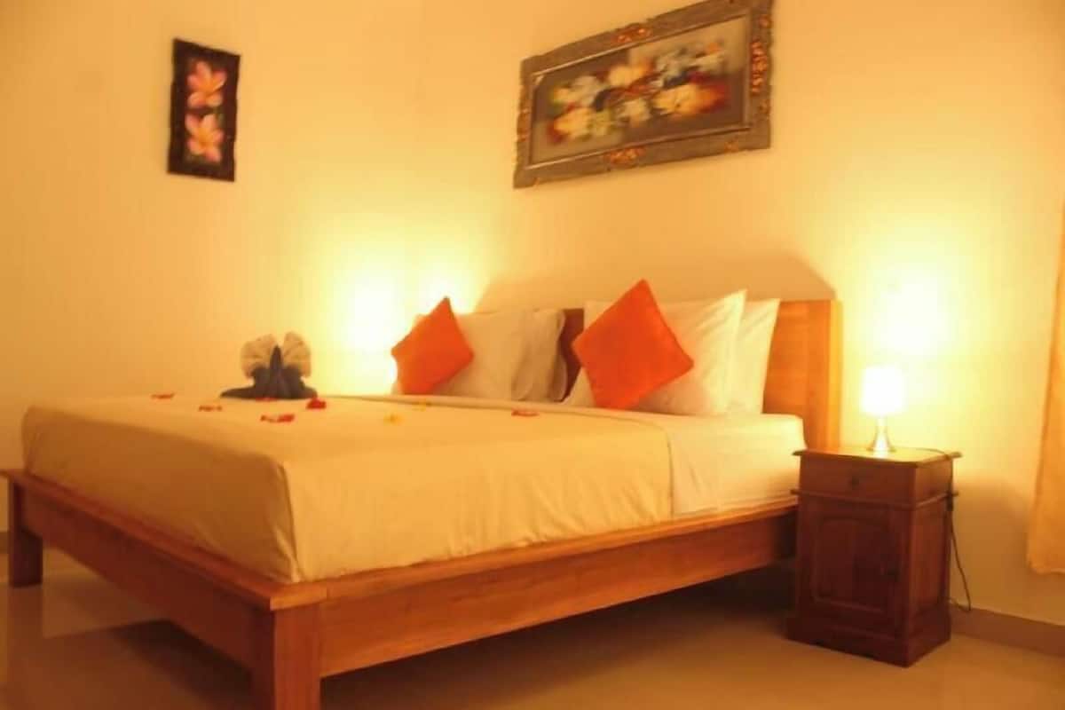 A bed with a wooden frame, white bedding, and orange pillows.