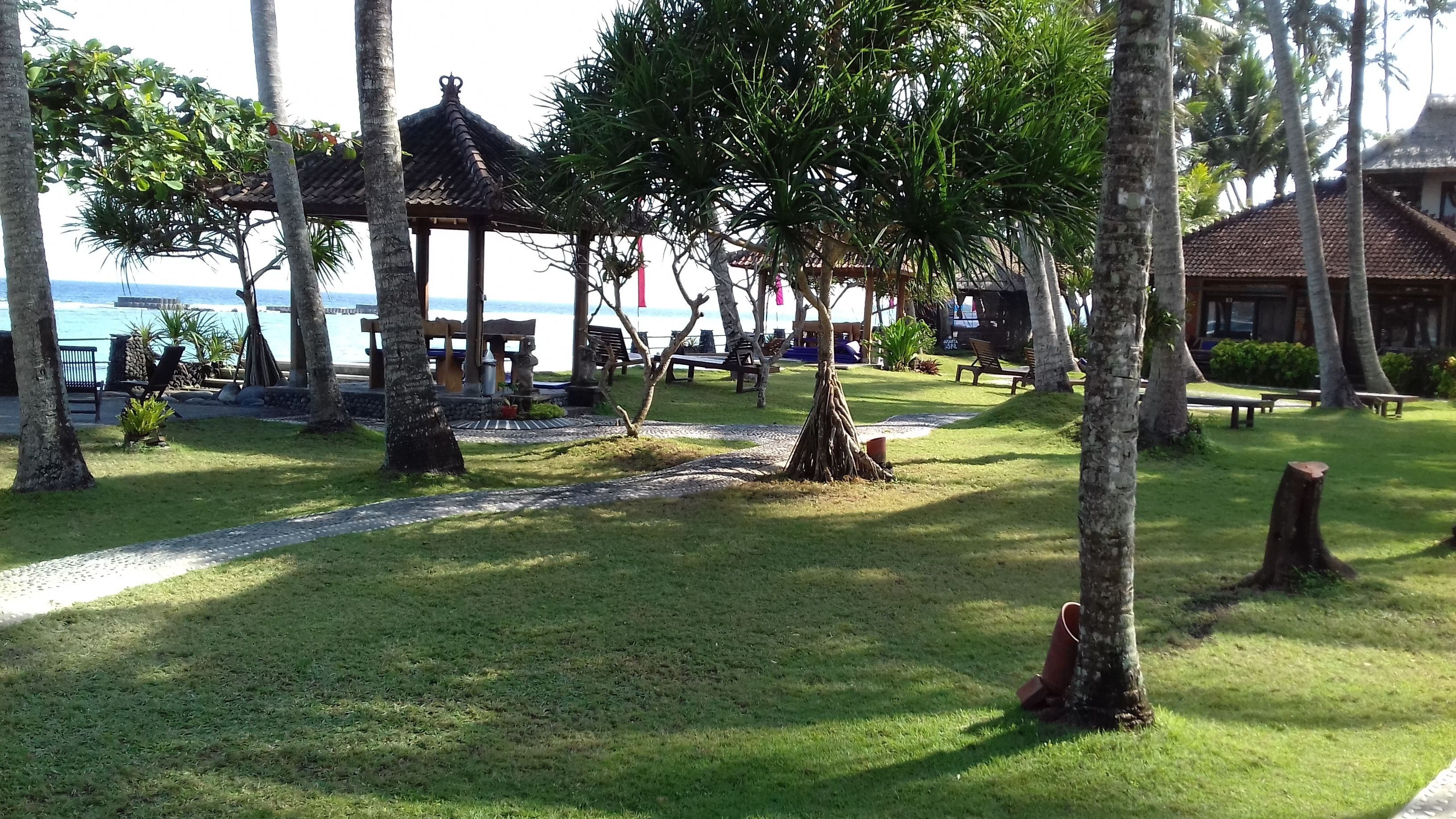 A serene outdoor area with a gazebo, benches, and a pathway leading to a beach.