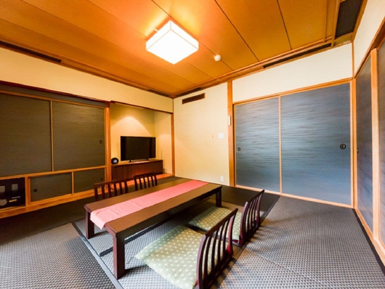 A traditional Japanese-style room with tatami flooring, a low table with cushions, and sliding doors.