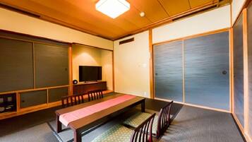 A traditional Japanese-style room with tatami flooring, a low table with cushions, and sliding doors.