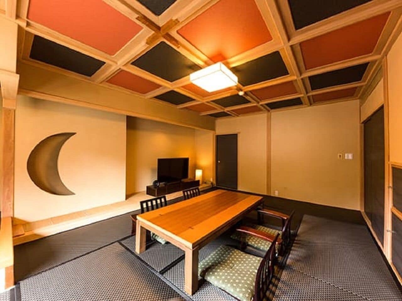 A traditional Japanese-style room with tatami flooring, a low table, and a television.