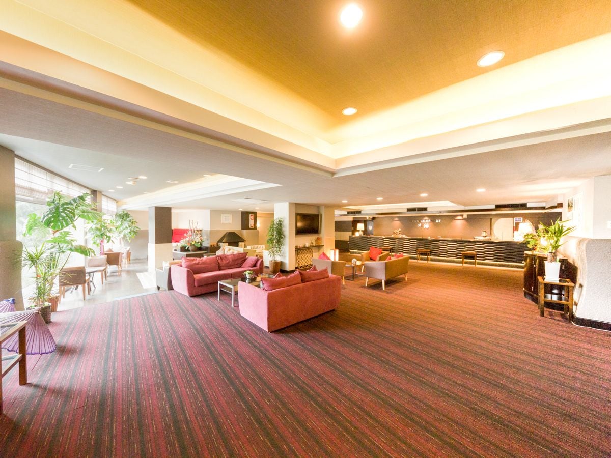 A spacious lobby with a red carpet, seating areas, and a reception desk.