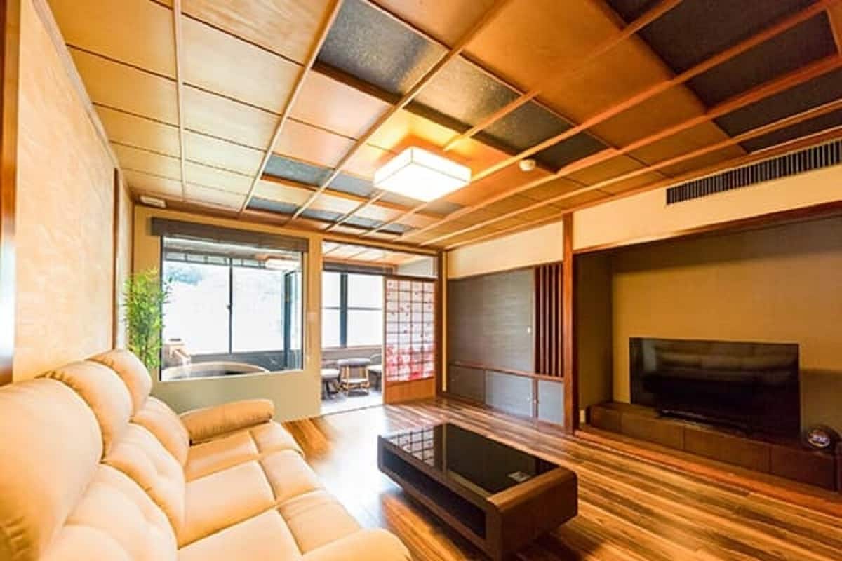 A modern living room with a sofa, TV, and wooden flooring.