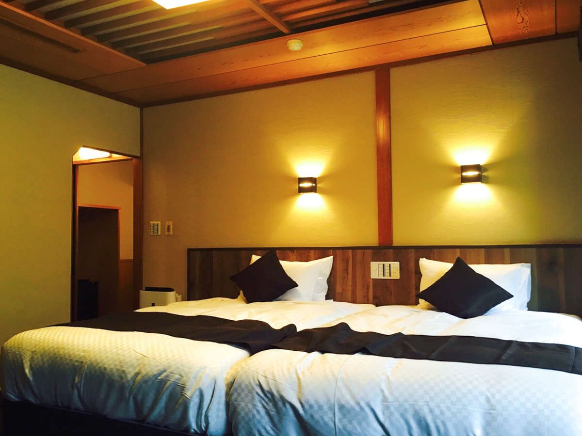A double bed with a wooden headboard, two wall-mounted lights, and a neutral-colored wall.
