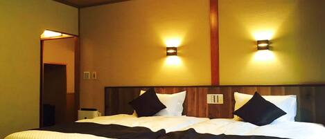 A double bed with a wooden headboard, two wall-mounted lights, and a neutral-colored wall.