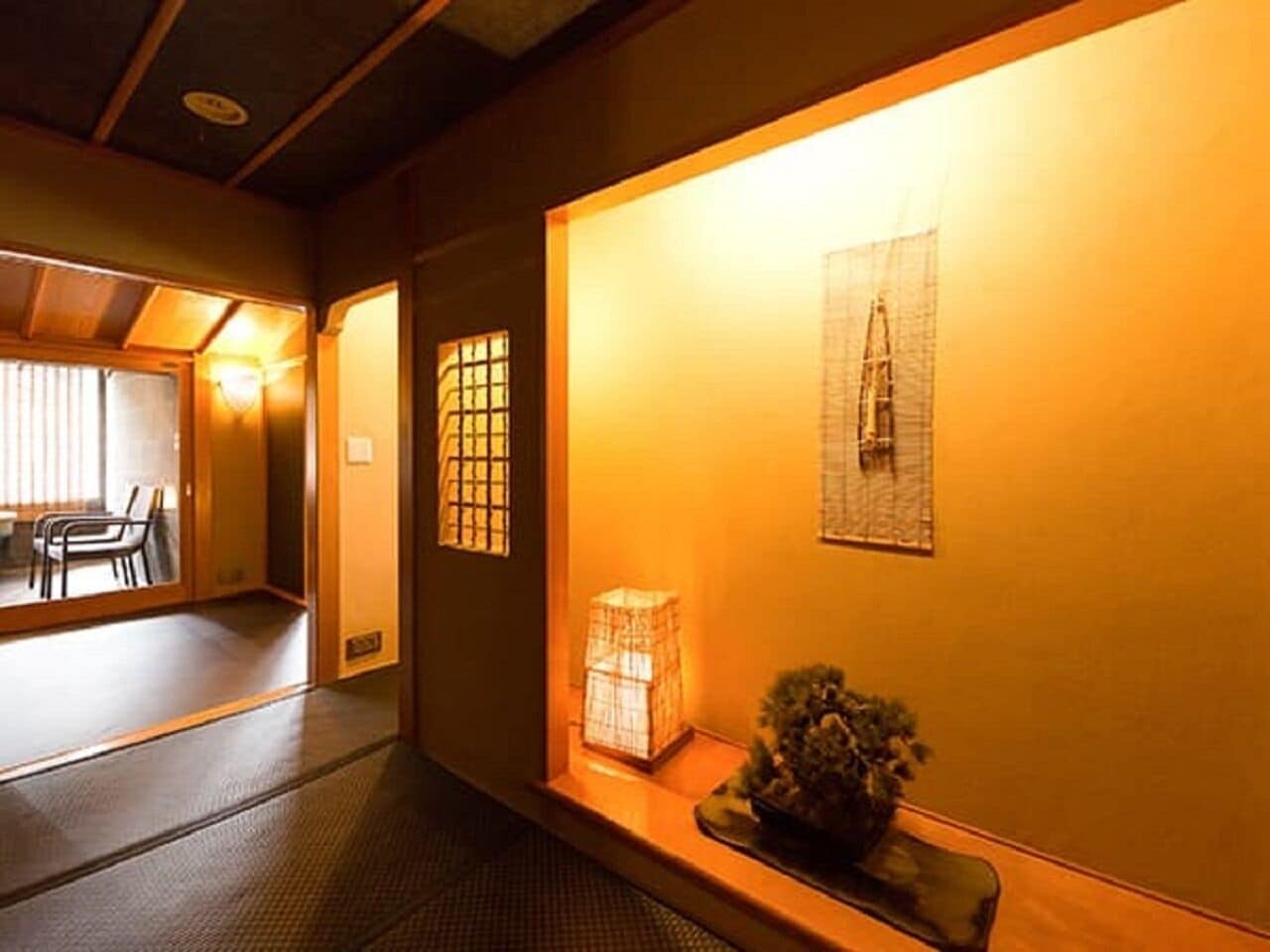 Un interior japonés tradicional con suelo de tatami, un banco de madera bajo y una pequeña planta en maceta.