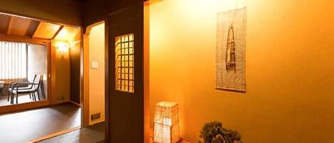 A traditional Japanese interior with tatami flooring, a low wooden bench, and a small potted plant.