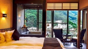 A hotel room with a large bed, a view of the mountains, a balcony with chairs, and a bathtub. - LiVEMAX RESORT KAWAJI (Nikko)