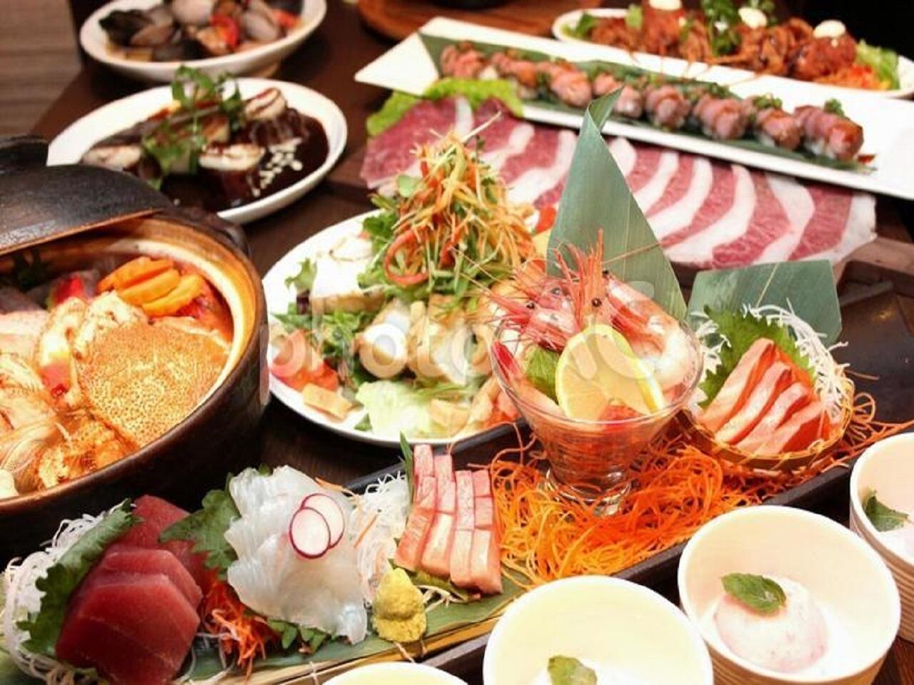 A variety of dishes including sushi, sashimi, and other seafood items, suggesting a Japanese dining experience.