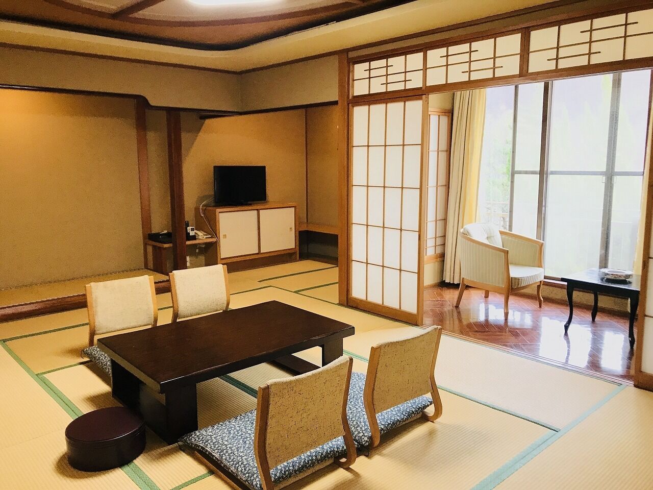 Una habitación japonesa tradicional con suelo de tatami, una mesa baja y sillas.
