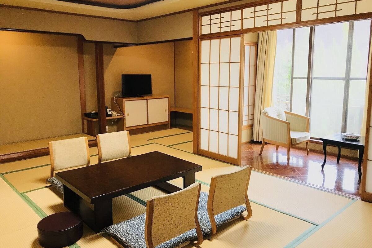 A traditional Japanese room with tatami flooring, a low table, and chairs.