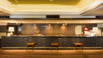 A reception area with a modern design, featuring a textured reception desk, two wooden chairs, and a visible sign that reads "LIVEMAX RESORT".