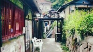 A narrow alleyway with stone walls, a wooden structure, and a white plastic chair. - Guest House Aloes House - Hostel (Onomichi)