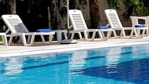 Une piscine avec des chaises longues blanches et un parasol blanc.