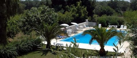 Een buitenzwembad, parasols bij het zwembad en ligstoelen