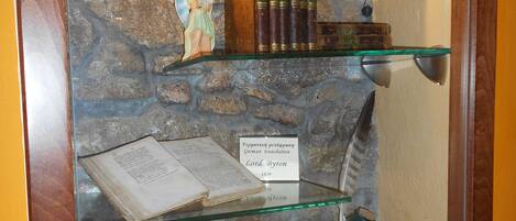 A display case with a stone wall background, featuring a statue, books, and an open book with a label.