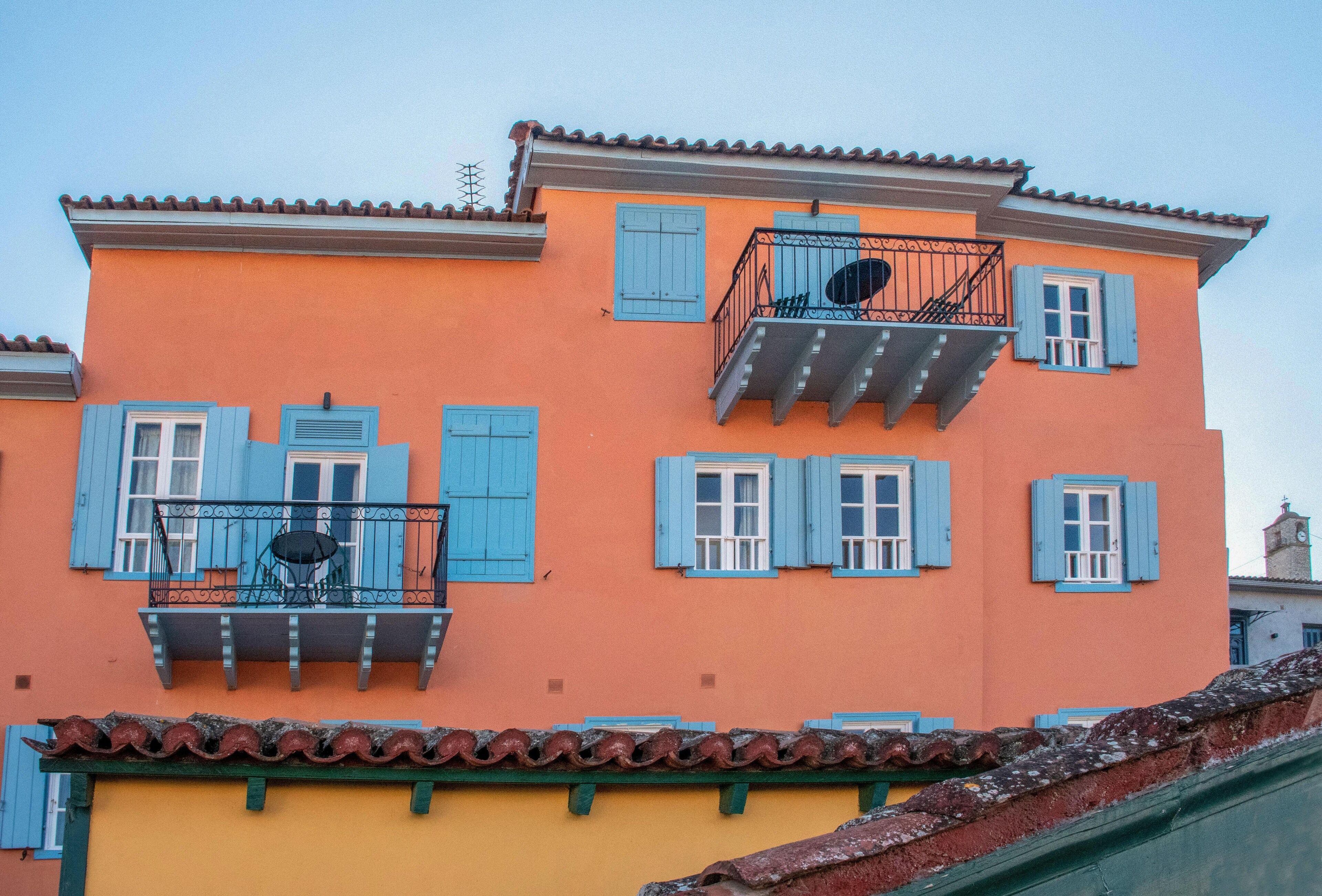 Un edificio con balcones, contraventanas azules y techo de tejas.
