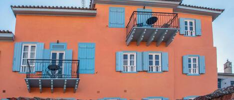 Un edificio con balcones, contraventanas azules y techo de tejas.