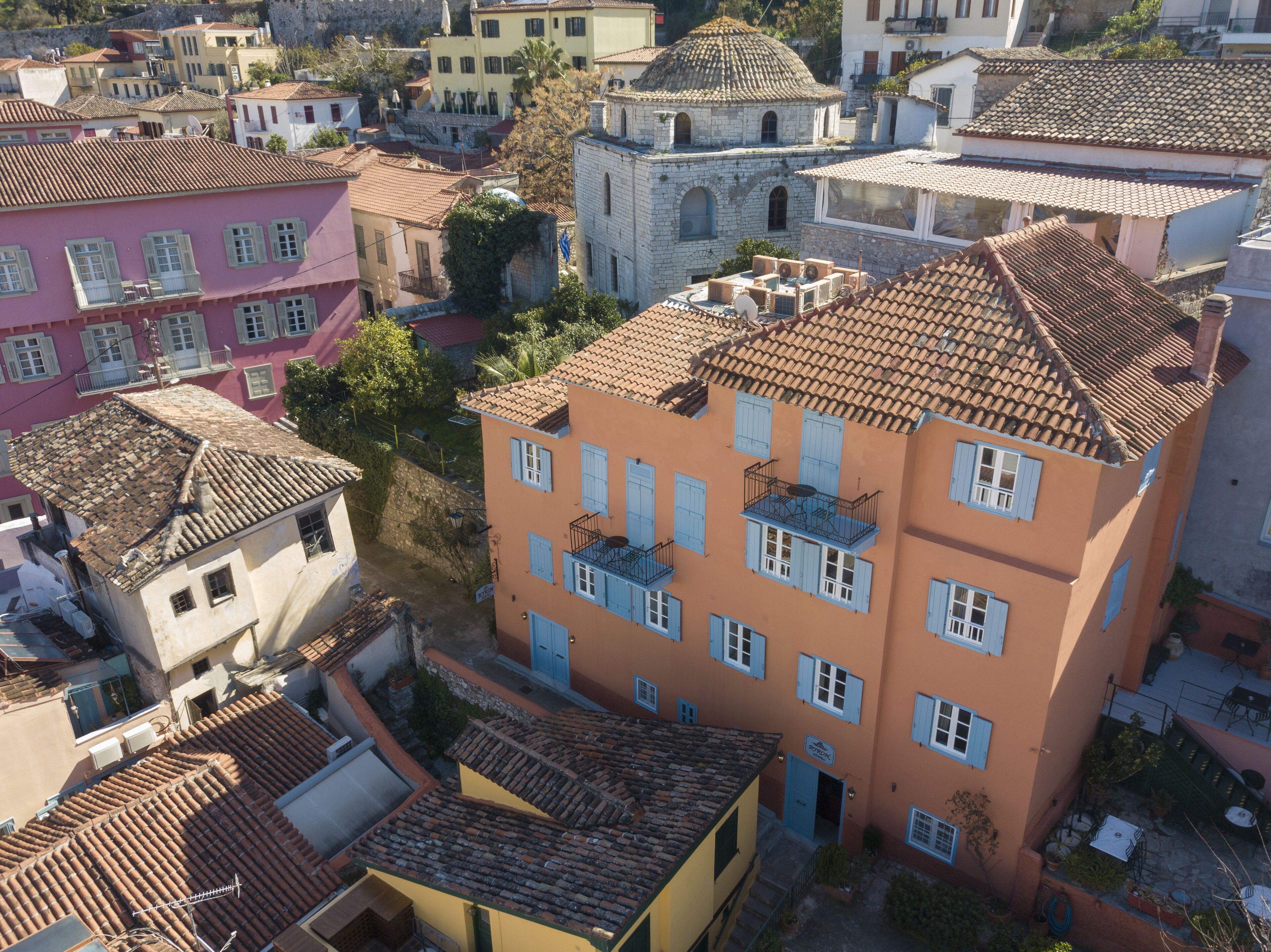 A multi-story building with a tiled roof, a balcony, and a door.
