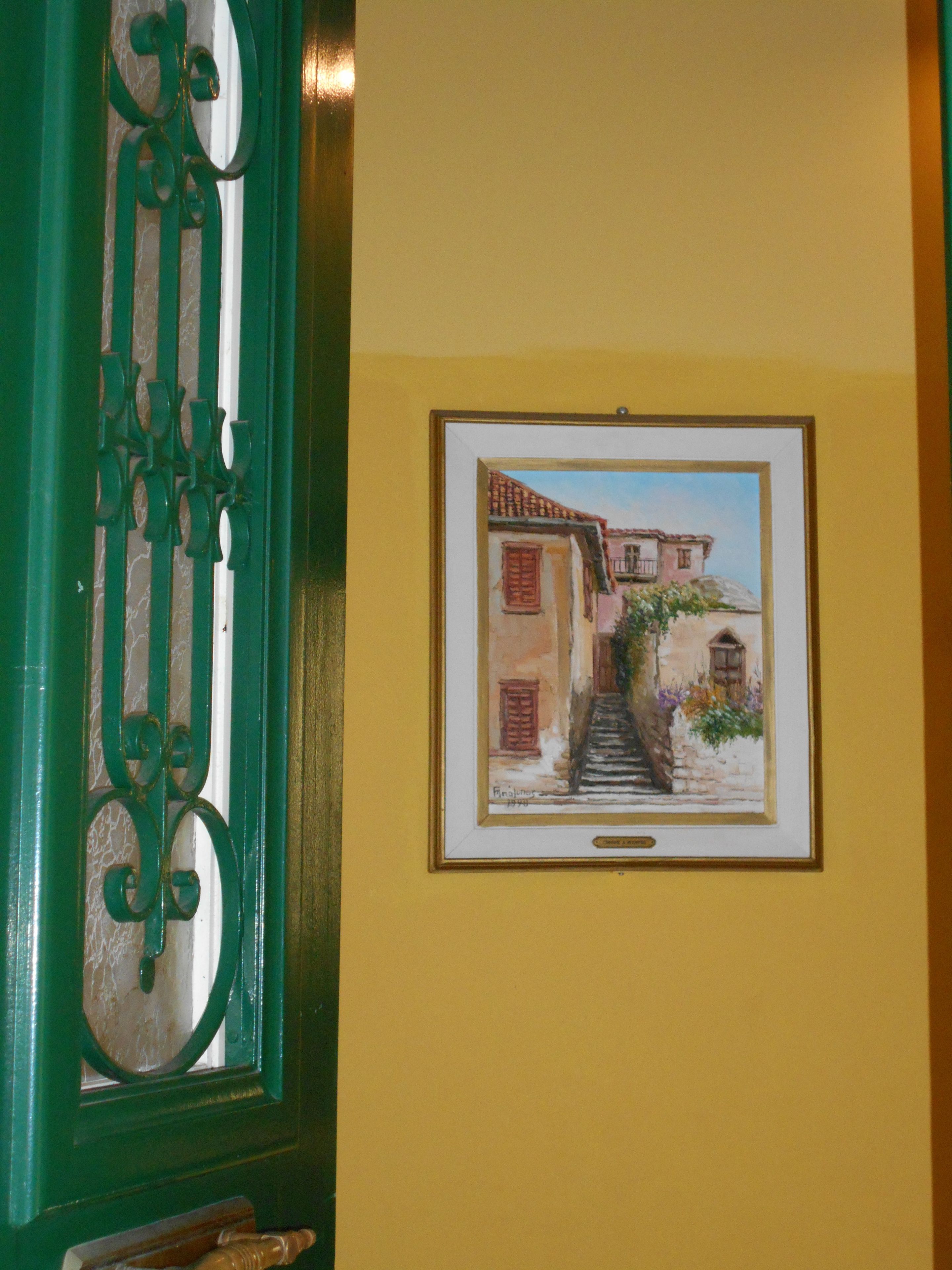 A framed painting of a street scene with buildings and a staircase.