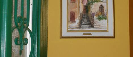 A framed painting of a street scene with buildings and a staircase.