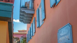 A narrow street with buildings painted in pastel colors, a sign for Byron Hotel, and a cobblestone path. - Byron Hotel (Nafplio)