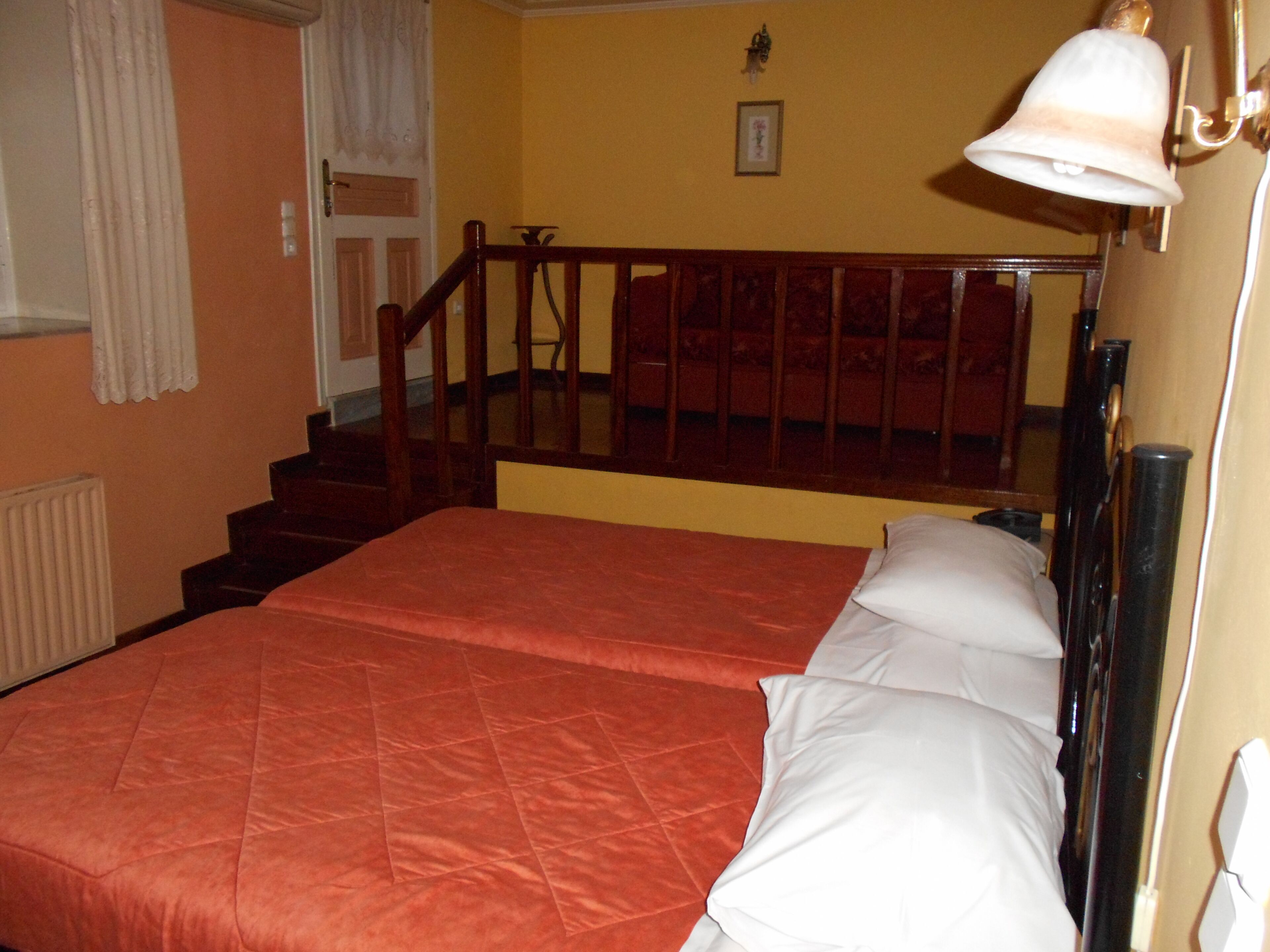 A hotel room with a bed, a staircase, and a wall-mounted lamp.