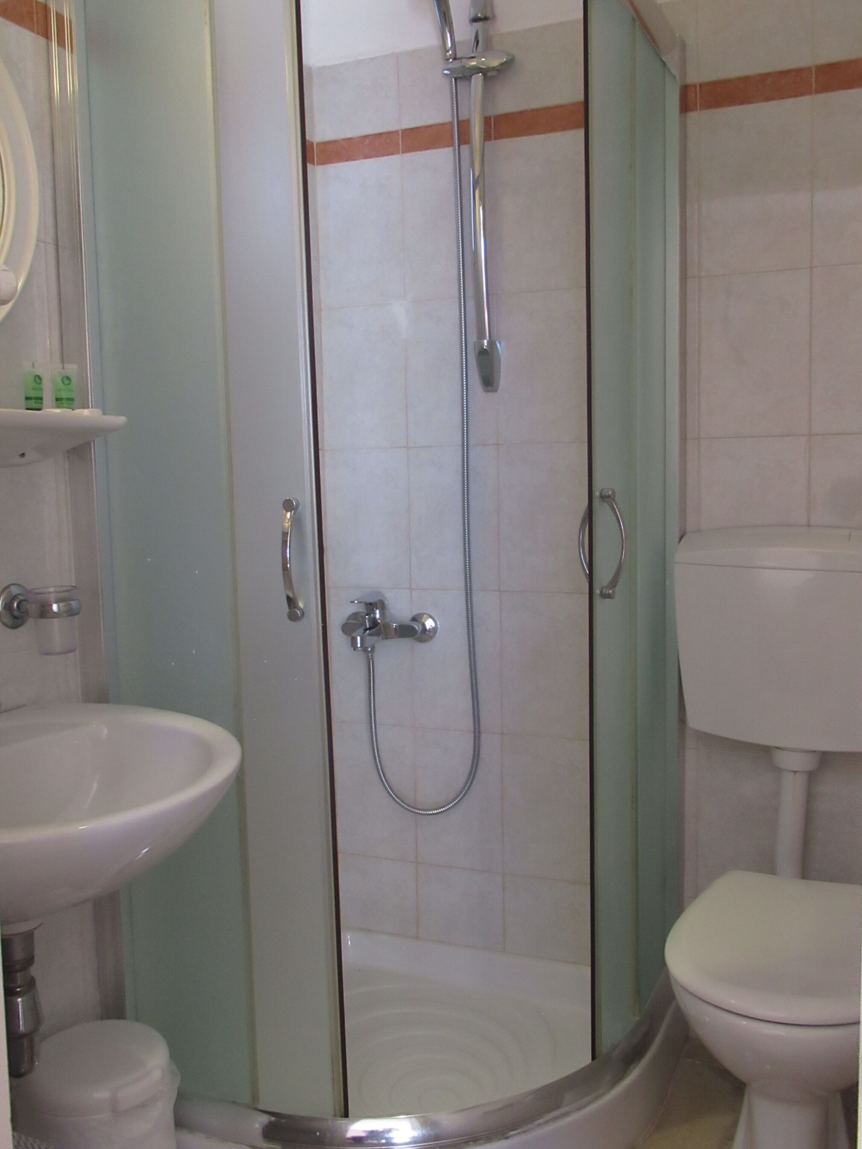 Un baño con ducha acristalada, lavabo e inodoro.